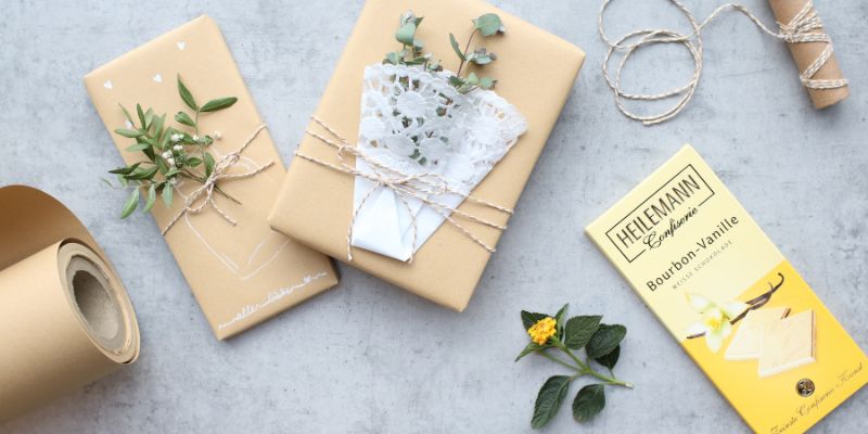 Geschenkpackung mit Kraftpapier, grünen Zweigen, Kordel und HEILEMANN Schokoladentafel.